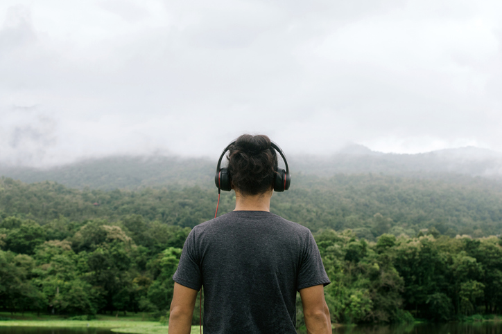 Man with headphones back view. looks into the distance with nature in the horizon.Amidst the beautiful nature.
